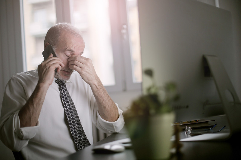 A
    stressed man talking on a cell phone.