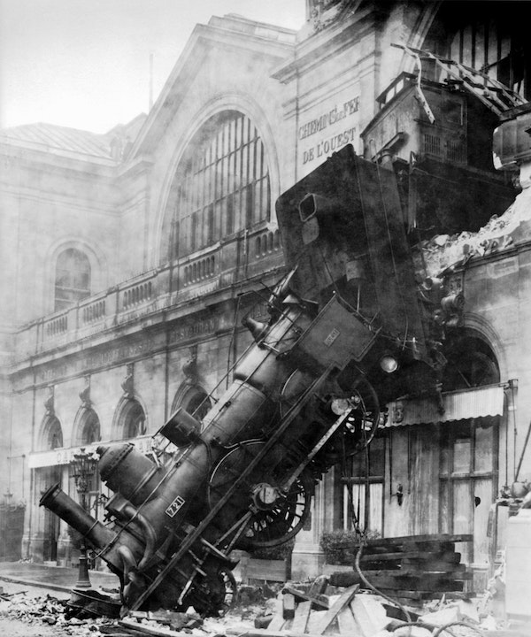 A train train
    has burst through the wall of a building and is resting, wrecked, on the
    ground.