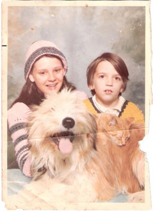Curtis and Gayle posing for a photo, with their dog Tommy and a cat
    lying atop the dog, asleep.