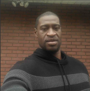 A selfie of a middle-aged black man wearing a black and grey knit hoodie.