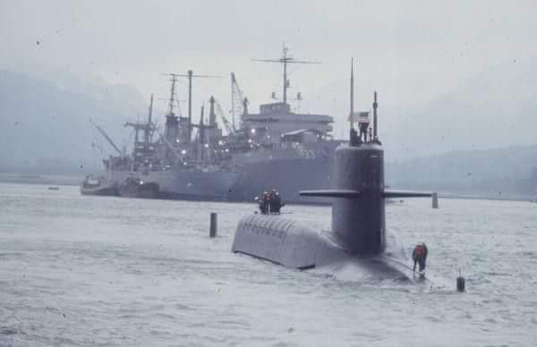 Grainy black and white image of a submarine and a ship.